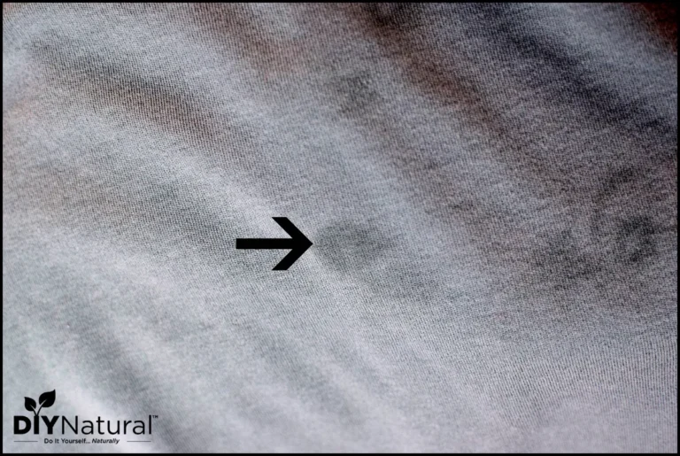 Essential oil stain on white cotton fabric with cleaning supplies nearby